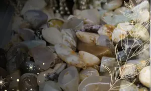 Gładkie kamienie, jak piasek pustyni, w odcieniach beżu, szarości i bieli, ozdobione delikatnymi, złotymi liśćmi i gwiazdkami.