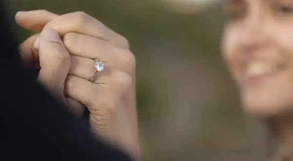 Delikatne pierścionki z diamentem, idealne jako pierścionki zaręczynowe. Biżuteria z diamentami na dłoni z jasnoróżowym manicurem.