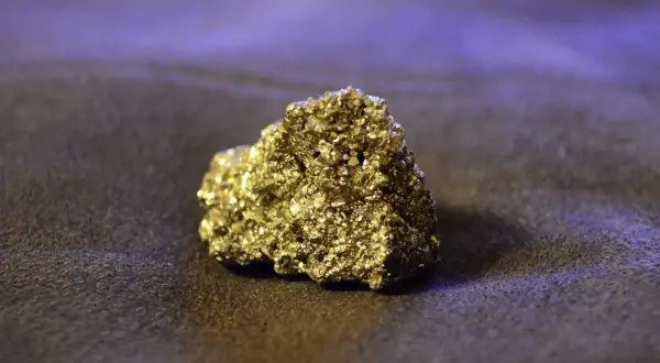 Błyszczący, złoty piryt, znany jako "złoto głupców", lśni na ciemnym tle. To fascynujący minerał, który często mylono ze złotem.