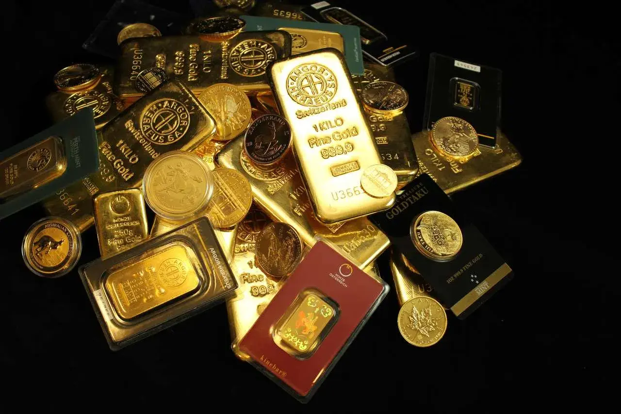 Złote sztabki i monety, w tym 1 kg sztabka złota, pokazują bogactwo i wartość.